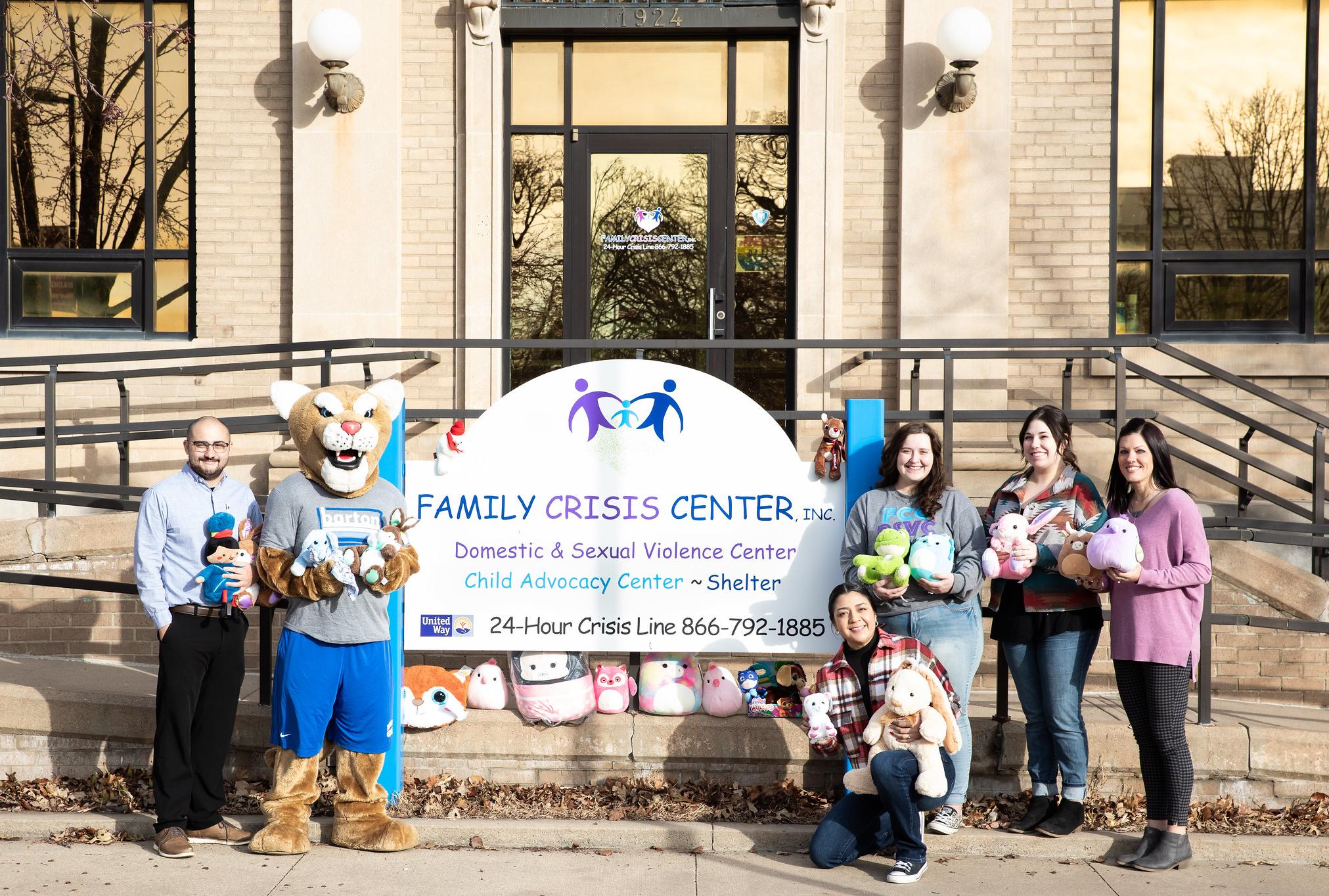 people standing in front of the family crisis center sign with stuffed animals