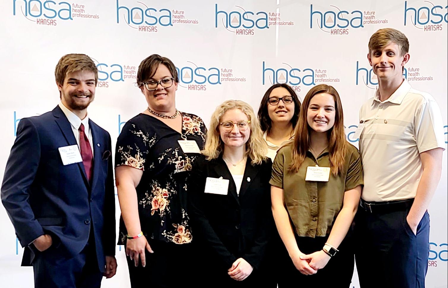 group of students standing in front of a HOSA backdrop