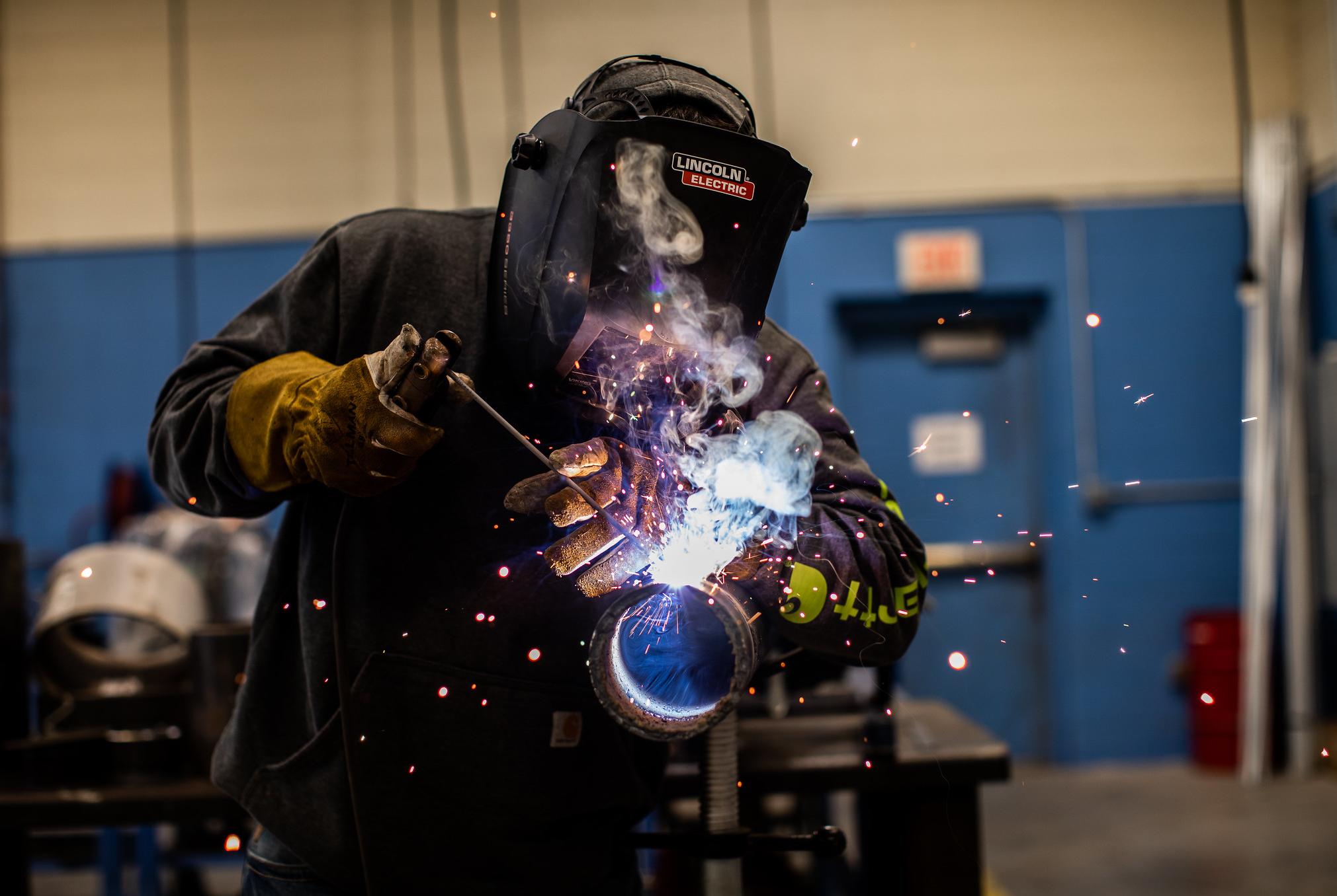 a student welds a piece of 4 inch pipe