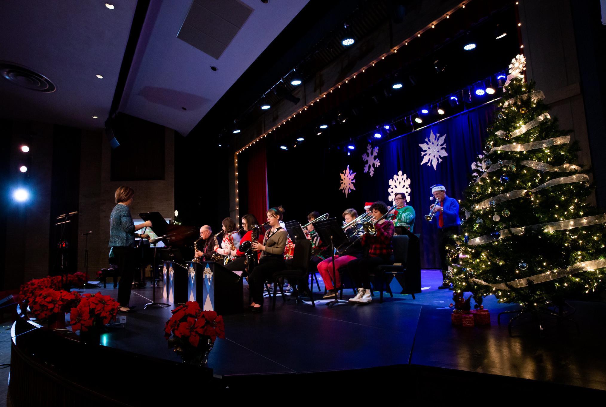 musicians playing on a stage decorated with a christmas tree and lights