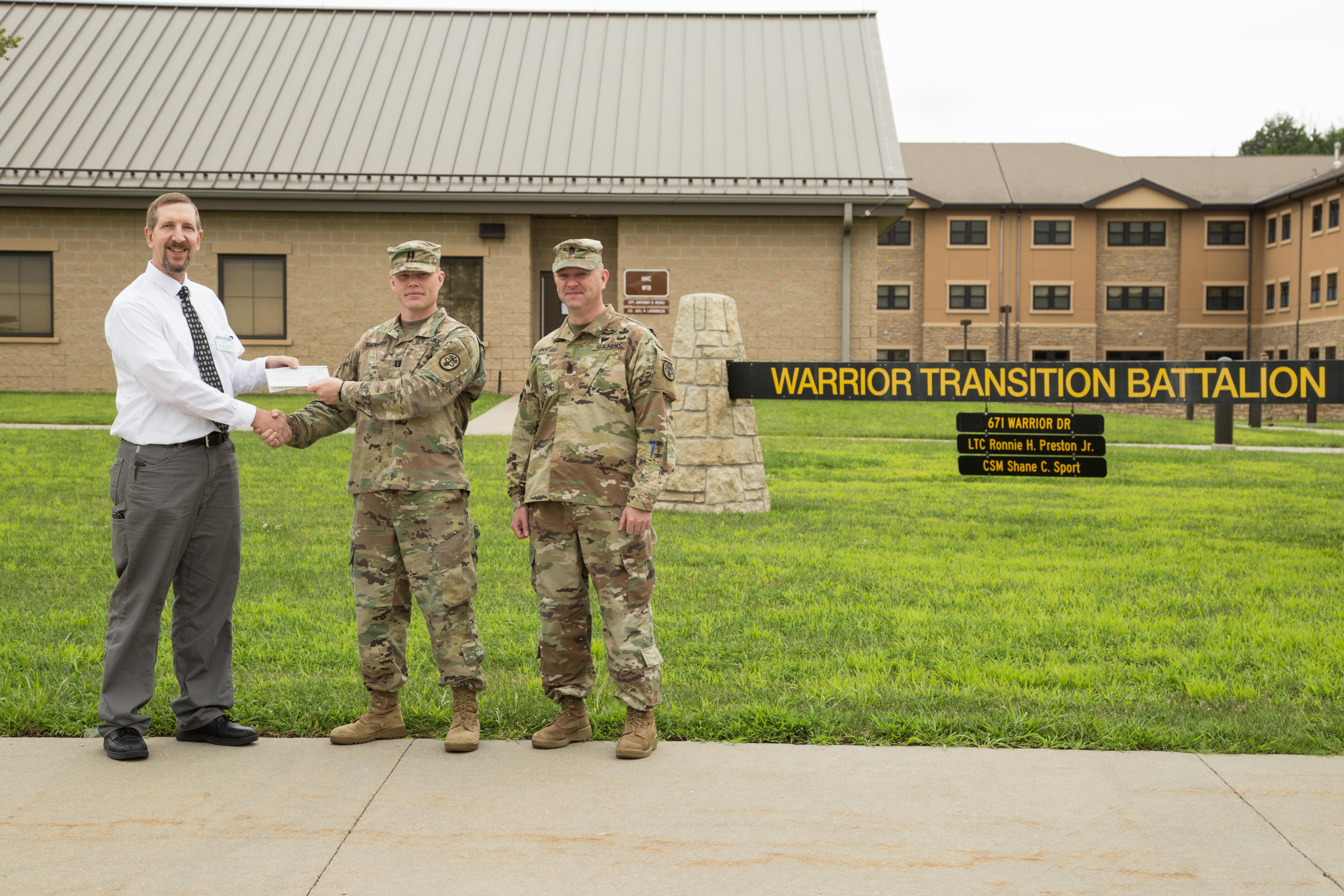 Kurt Teal, Dean of Fort Riley Academics, Technical Education and Military Outreach Programs at Barton Community College, presents a check for $3,250 to Bravo Company Commander Daniel Sheninger and Command Sergeant Major Shane Sport. 
