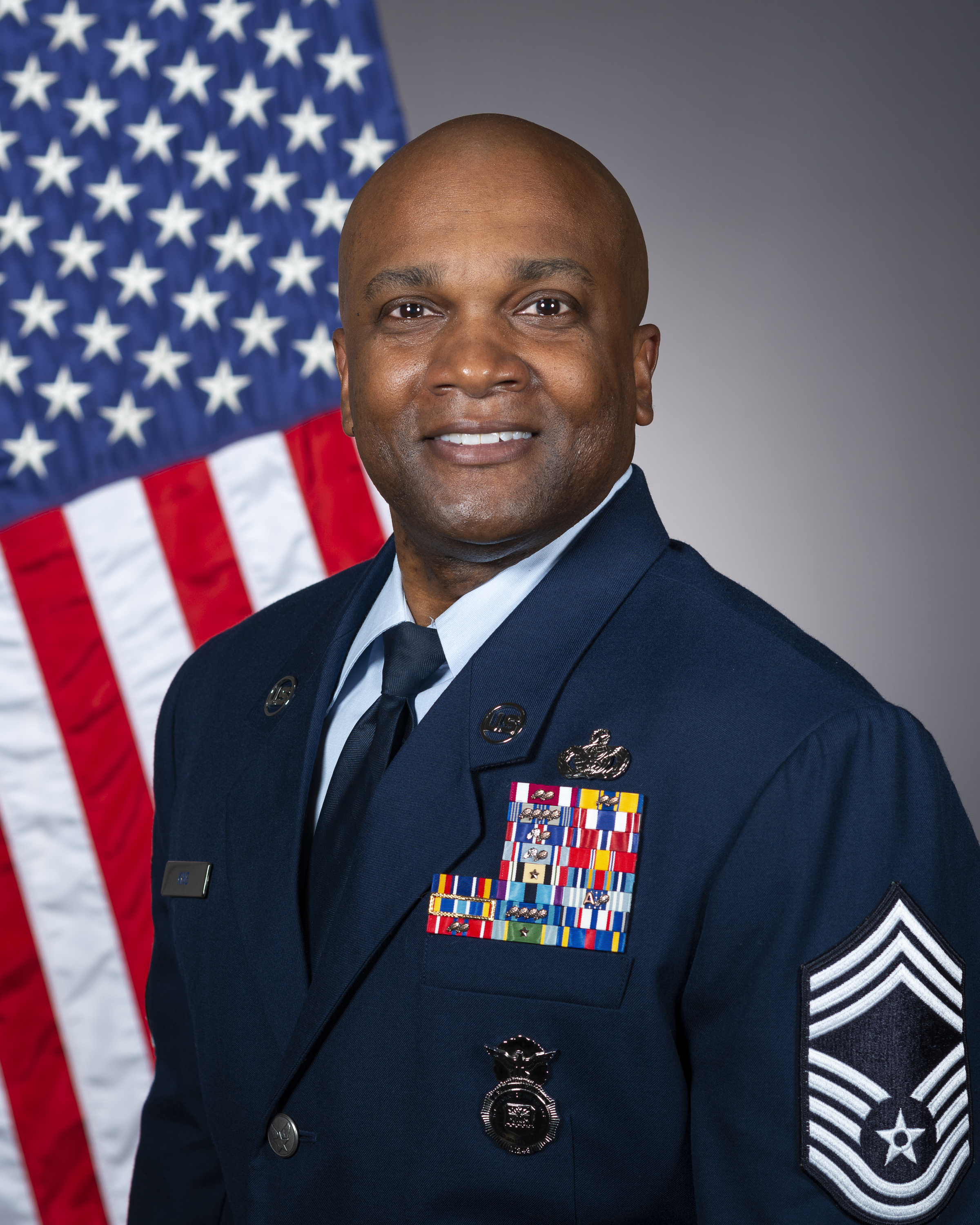 man in airforce formals with American flag behind him