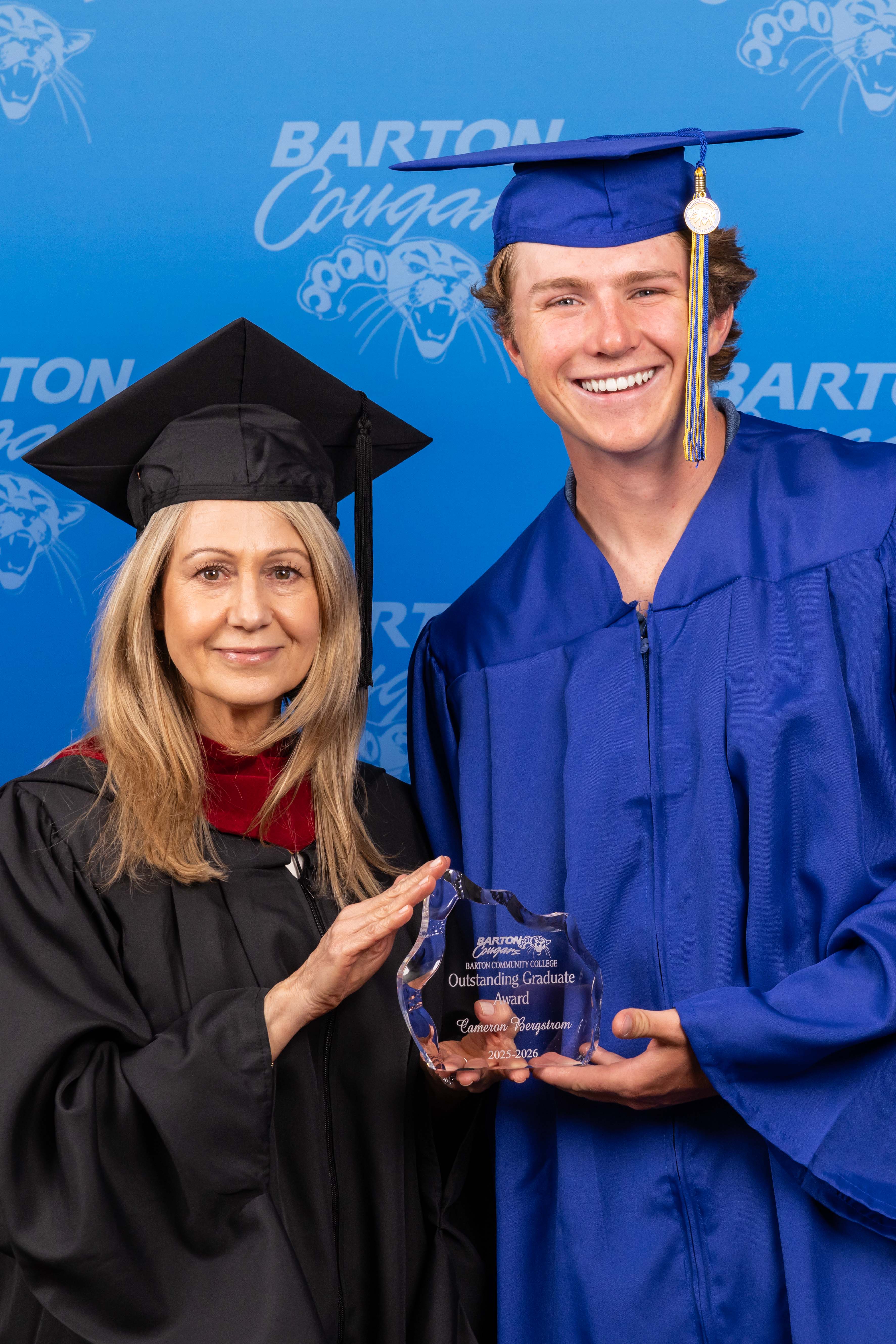 administrator holding an award with a student