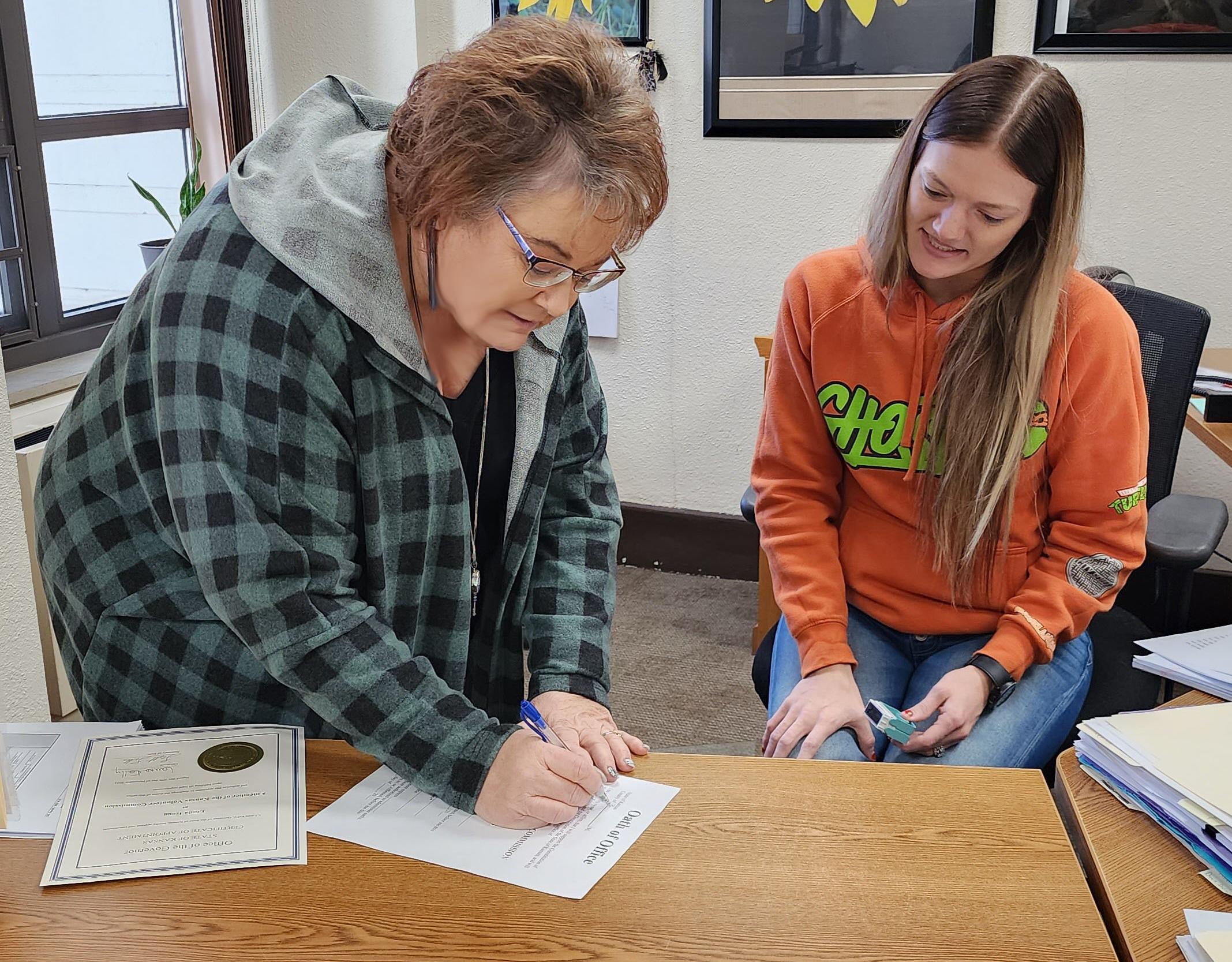 woman signing governor's appointment document with a notary public