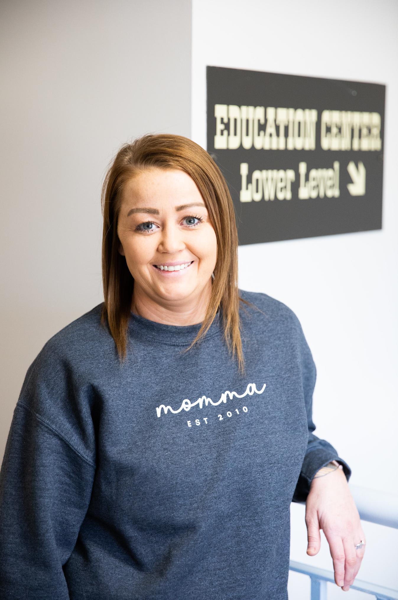 woman smiling by sign that says education services