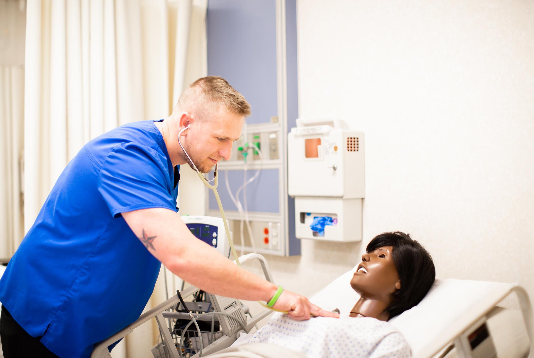 man using stethoscope on a mannequin