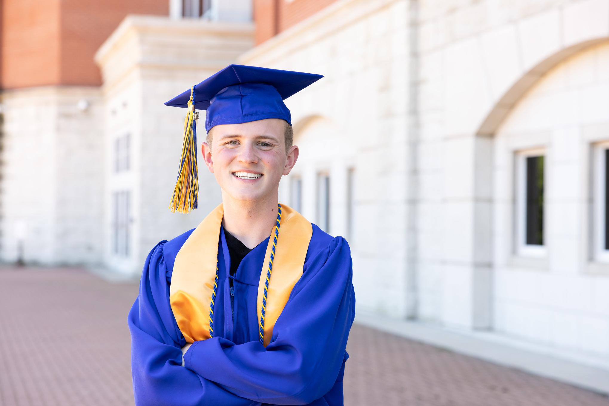 student in a graduation cap and gown outside of a building