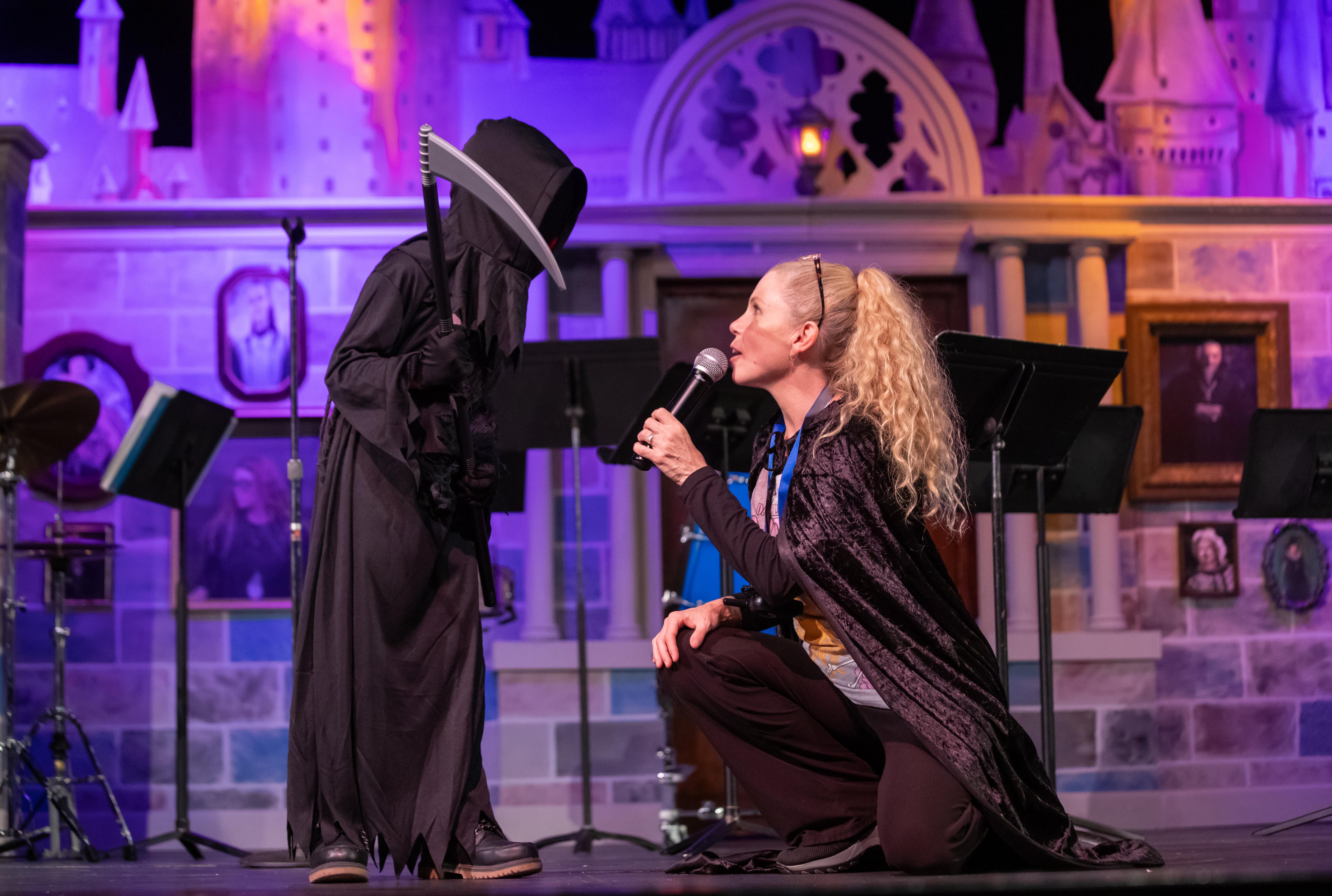 host of costume contest talks to grim reaper youth costumed person