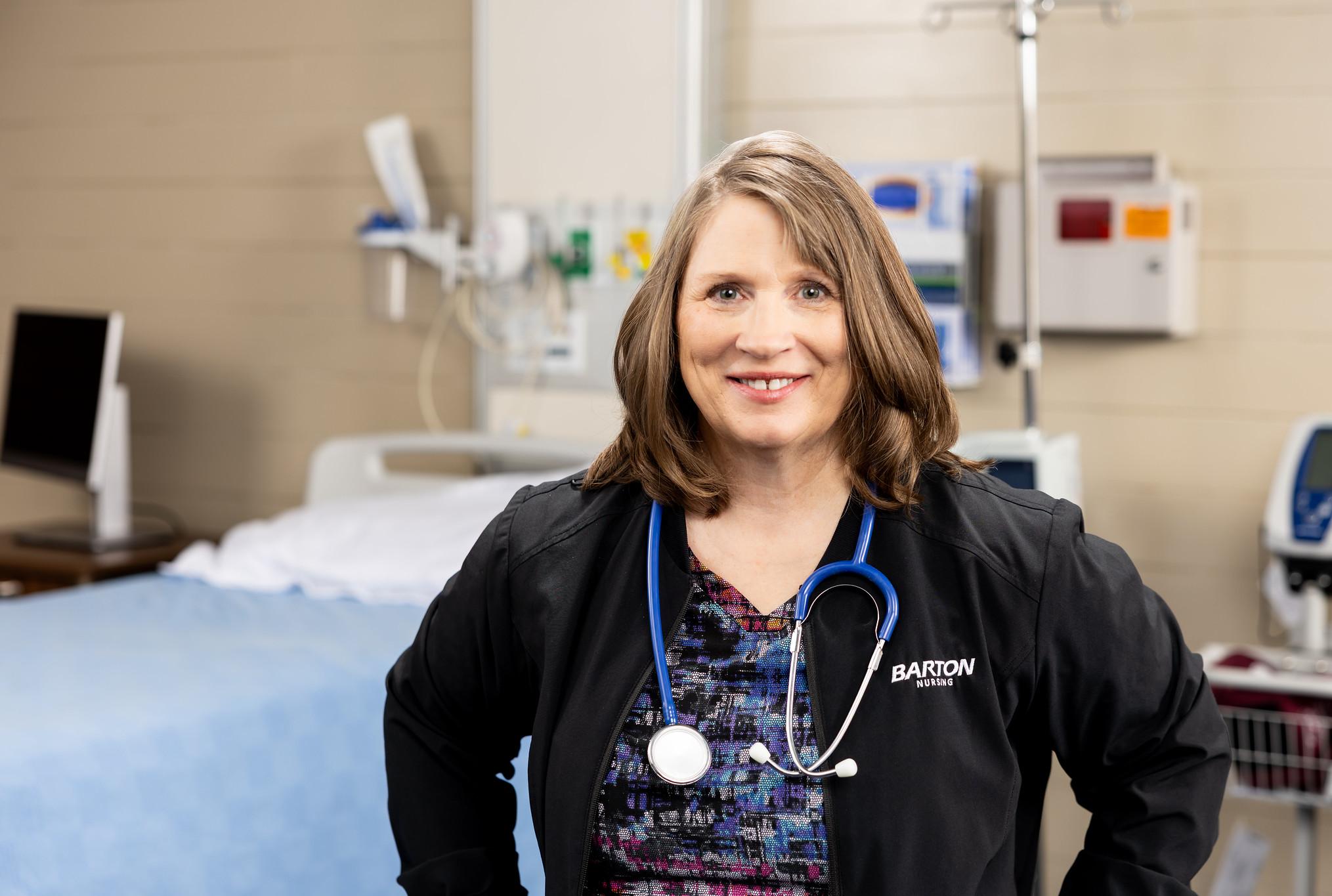nurse in black scrubs in simulation lab smiling at camera