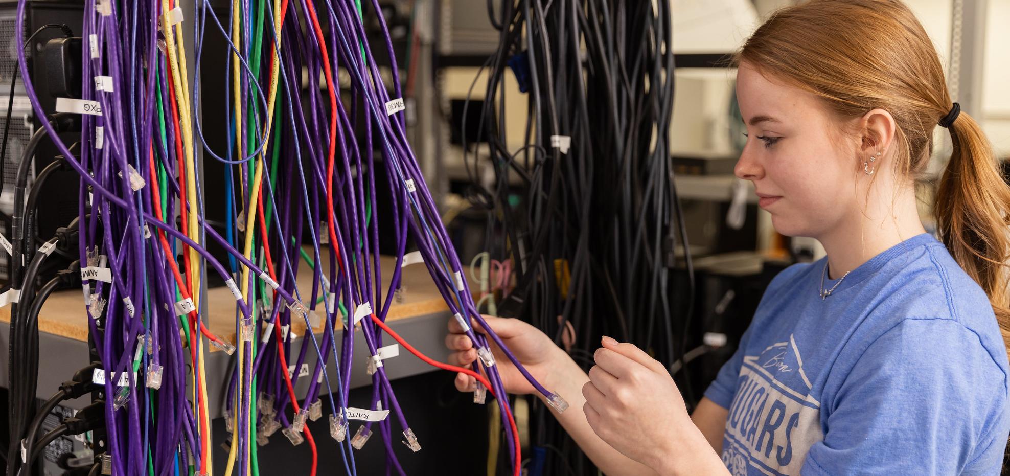 Student works on cables for computer networking class