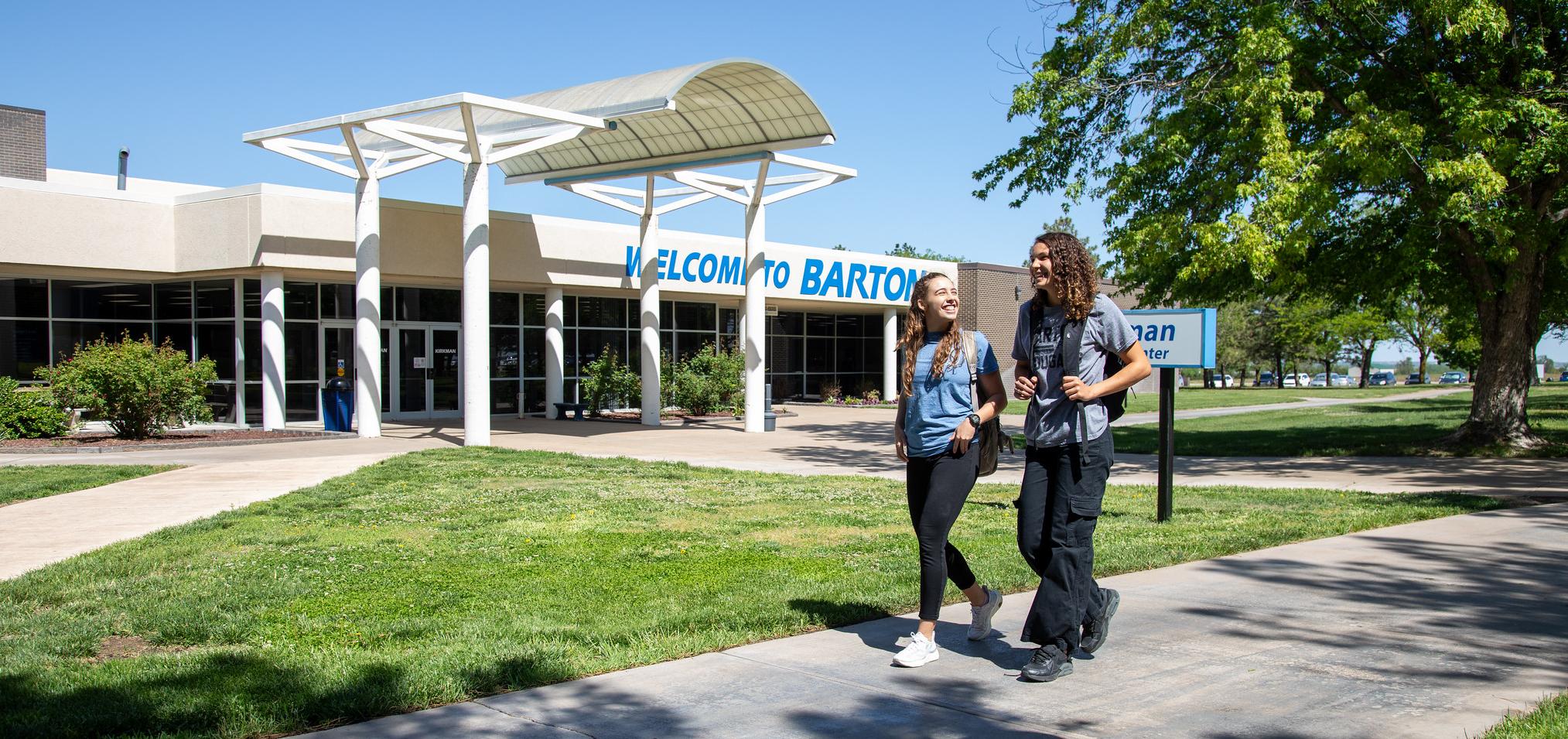 Barton students walk in front of Welcome to Barton sign on campus